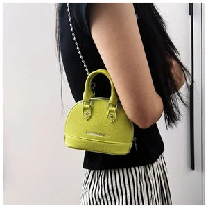 Model showing side view of mini lime green shell crossbody bag with silver chain strap