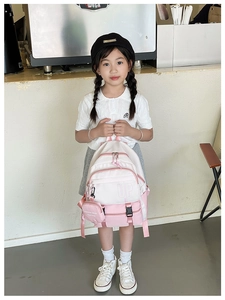 Pink and white kid's backpack detail featuring the UP logo and detachable coin purse