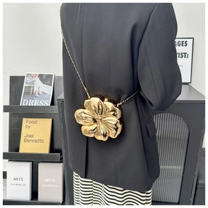Detail view of a 3D gold flower-shaped metal chain bag with elegant relief carving