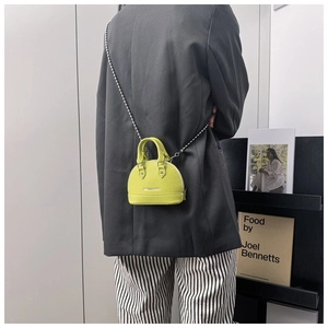 Detail of neon green shell bag with leather texture and silver ball chain strap