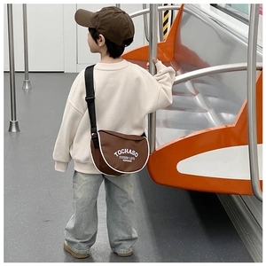 Détail d'un sac bandoulière marron pour enfant avec passepoil blanc et lettrage imprimé