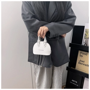 Close-up of mini white shell bag with silver bead chain strap and fashion text detail