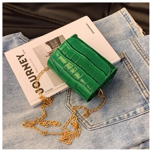 Detailed macro of bright green mini bag with faux crocodile pattern and gold chain strap