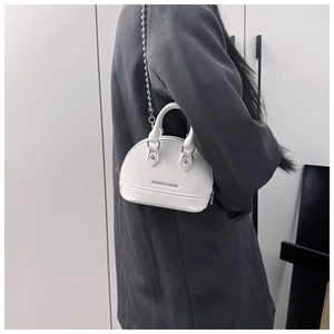 Detail of white shell handbag with silver ball chain strap and leather texture
