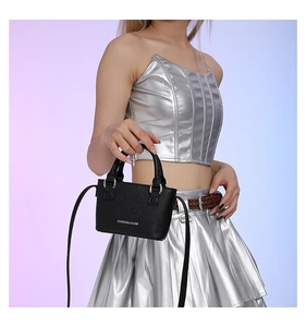 Mini black lychee leather crossbody bag with silver lettering on a fashion model