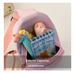 Internal view of pink canvas chest bag showing storage capacity with a cartoon notebook
