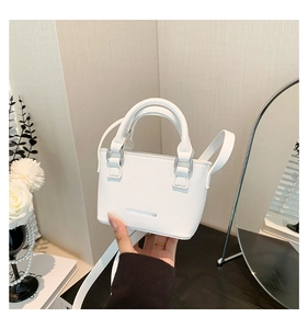 Detail of white litchi pattern mini bag with silver metal logo and dual handles