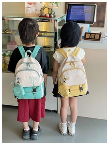 Detail of color-block kids backpacks with UP lettering and mini round coin purses