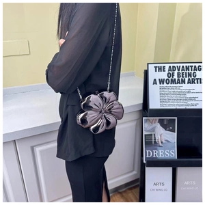 Close-up of a silver flower-shaped hard shell crossbody bag with a metallic chain strap