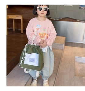 Olive green canvas drawstring backpack styled with a casual kids pink sweatshirt