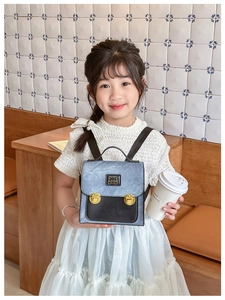 Toddler backpack detail showing bear metal plaque and blue-black color block design