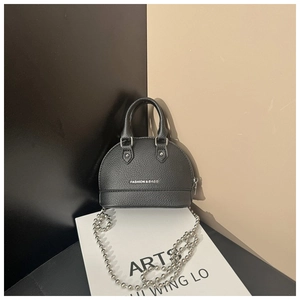 Detail of black shell-shaped handbag showing lychee pattern leather and silver bead chain
