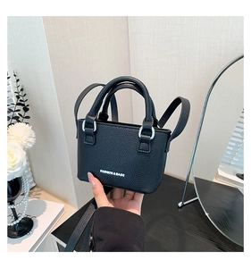 Close-up of black litchi leather mini handbag with FASHION & BAGS logo and silver hardware