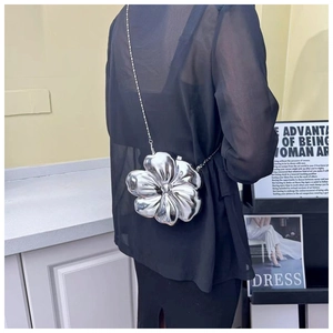 Detail of silver metallic flower crossbody bag with chain strap on a model