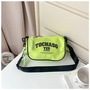 Close-up of neon green nylon crossbody bag for kids featuring black text print and wide strap