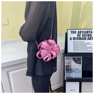 Close-up of pink metallic flower-shaped clutch bag with silver chain strap worn by a model