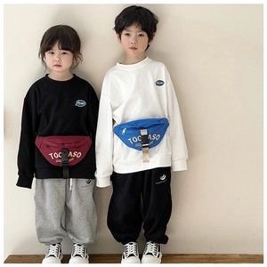 Close-up of stylish canvas waist bags for kids with TOC ASO letters on maroon and blue fabric