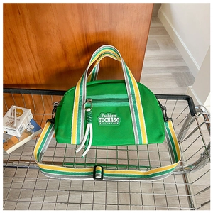 Détail du sac bandoulière en toile verte avec sangles rayées et broderie dans le panier