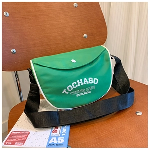 Vue détaillée d'un sac bandoulière vert en demi-lune avec liseré blanc et bouton
