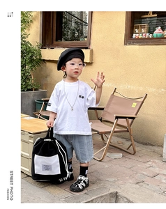 Street style kids outfit featuring a black and white drawstring backpack with a white tee