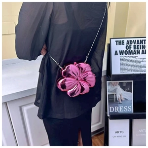 Close-up of pink metallic flower-shaped shoulder bag with silver chain on model