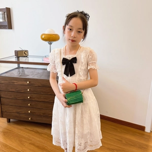 Girl's white lace puff sleeve dress with a black bow and floral crochet pattern