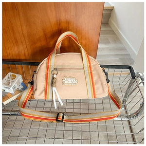 Détail d'un sac bandoulière beige en tissu Oxford avec sangles rayées dans un chariot