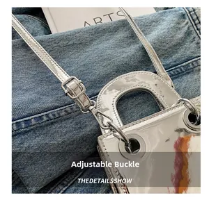 Détail de la boucle en métal et de la bandoulière en cuir verni argenté du petit sac