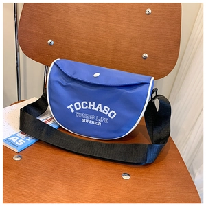 Sac bandoulière bleu pour enfants avec lettrage blanc et bandoulière noire sur chaise
