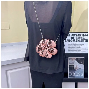 Detail of rose gold flower evening bag with metallic chain strap worn by a model