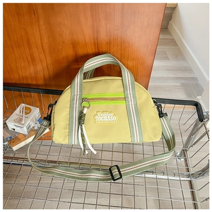 Détail du sac en toile jaune clair avec sangles rayées dans un panier en métal