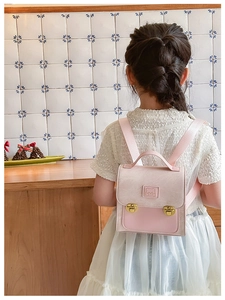 Detail of pink bear-patterned toddler backpack with gold metal buckles and stitching