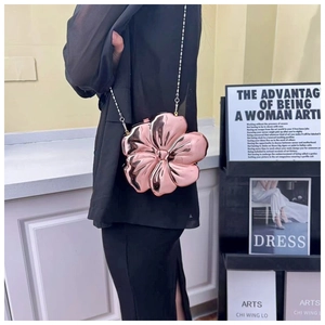 Detail of rose gold flower-shaped clutch bag with elegant metal chain on model