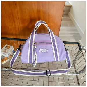 Détail du sac à main violet en tissu Oxford avec bandoulière rayée et patch brodé