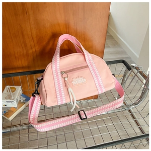 Gros plan détaillé du sac rose en tissu oxford avec écusson et bandoulière à carreaux