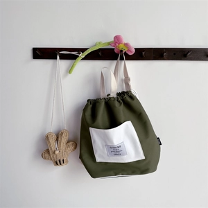 Detail of dark green kids backpack with white pocket and textile shoulder straps