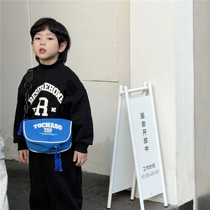 Outdoor shot of a child wearing a trendy blue crossbody messenger bag with letter print