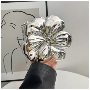 Detail of silver metallic flower clutch with mirror finish and slim chain strap