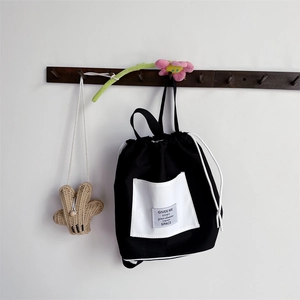 Detail of black and white canvas bucket backpack with drawstring and square pocket