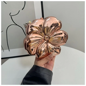 Macro detail of rose gold flower clutch bag with reflective mirror finish and chain