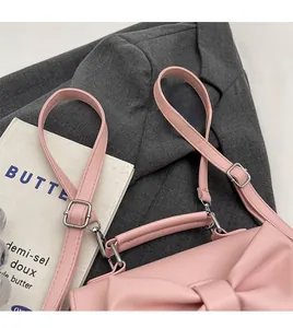 Detail of soft pink leather bag featuring a large bow and adjustable silver buckle strap