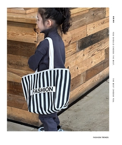 Rear view of a child wearing the black and white striped canvas bag with FASHION patch