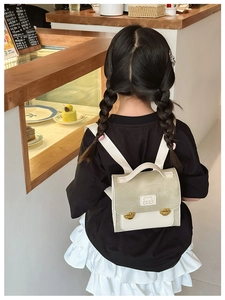 Rear view of child wearing a light green bear backpack in a cozy cafe setting