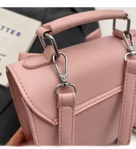 Detail of pink leather handbag showing silver hardware and reinforced handle stitching