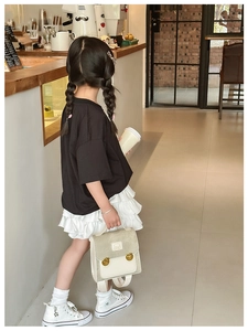 Detail of a girl carrying a beige bear backpack with a trendy casual summer outfit