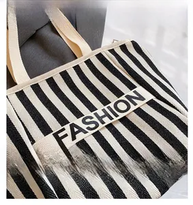 Close-up of black and white striped tote bag with Fashion lettered canvas strap