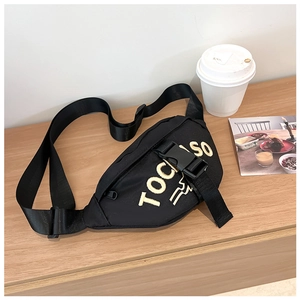 Detail of black canvas waist bag with yellow letter embroidery on a wooden table