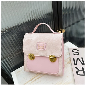 Close-up of pink canvas bag with gold push-locks and a cute bear patch on marble surface