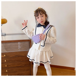 Detail of child wearing a quilted purple crossbody bag with cream fashion two-piece set
