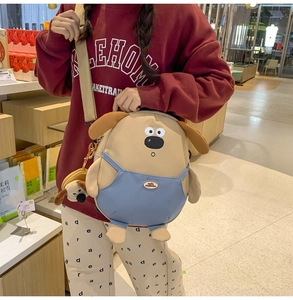 Dettaglio della borsa a tracolla cane in peluche beige con salopette blu e ciondolo